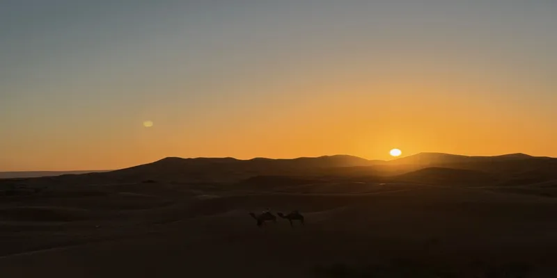 pustynia Sahara - symbol wschodu słońca oświetlającego powoli piaszczyste wydmy