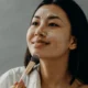 Kobieta nakłada krem pielęgnacyjny na skórę twarzy. Zdjęcie: Polina, pexels.com